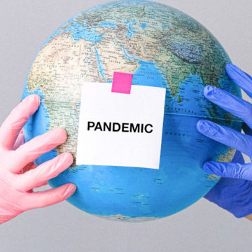 2 Personen mit medizinischen Handschuhen halten eine Weltkugel hoch. Vorne klebt ein Zettel mit der Aufschrift "PANDEMIC"